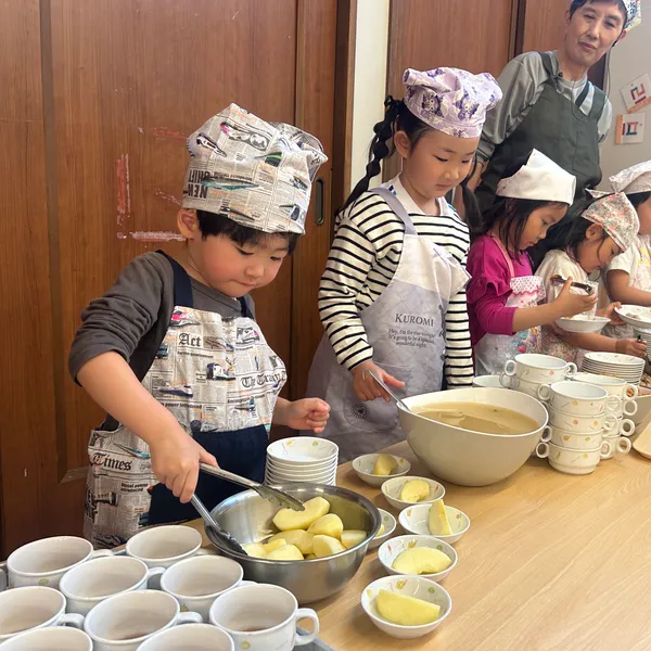 コック帽とエプロンで給食を配膳する子どもたち